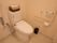 可動式の手すりや、緊急呼び出しボタンが設置されているトイレである。予備のトイレットペーパーがかごに入れられて置かれている。