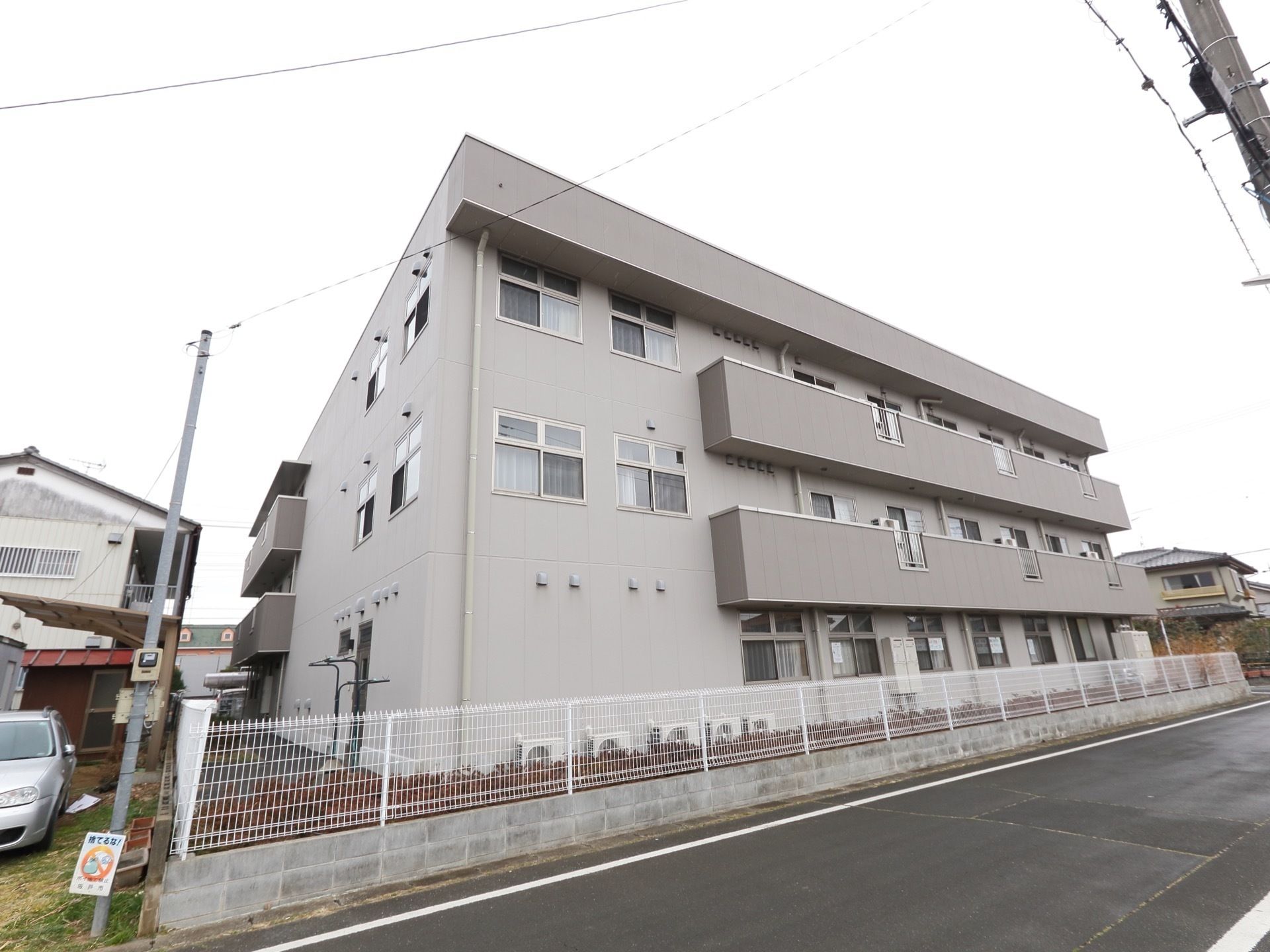 施設の周辺に高い建物はなく、日当たりの良い立地となっている。また敷地内にはガーデンスペースがあり、柵が取り付けられている。