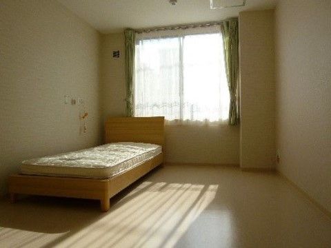 窓が大きく、採光により室内が明るくなっている。壁際にベッドが置かれ、エアコンが完備されている。枕元にはナースコールが設置されている。