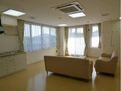 大きな窓がある明るい部屋にソファが置かれ、座ると窓側を向く形になっている。室内にはキッチンも設置されている。
