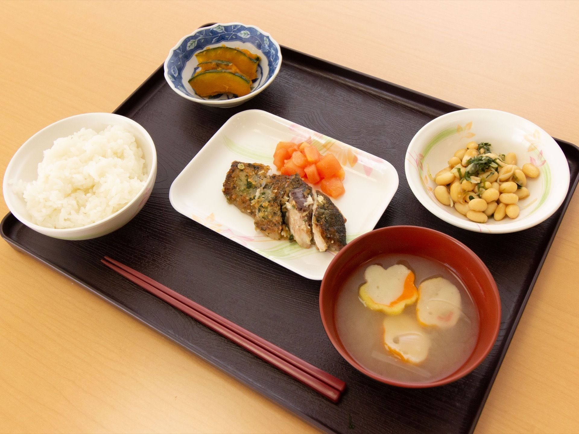 彩鮮やかな食事である。かぼちゃの煮物や魚料理、豆を使った副菜など栄養バランスの良い内容になっている。