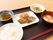 黒いトレーの上に一人前の食事が置かれている。ご飯やみそ汁の他に、メインの魚料理、副菜が並べられている。