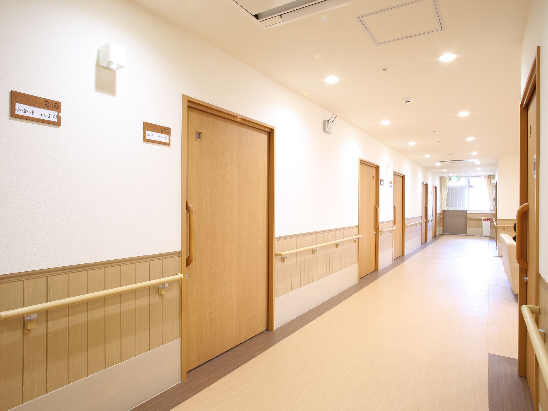 居室前の廊下は広さにゆとりがある。居室の扉は出入りのしやすい引き戸になっている。扉の横には部屋番号と入居者様のお名前が表示されている。