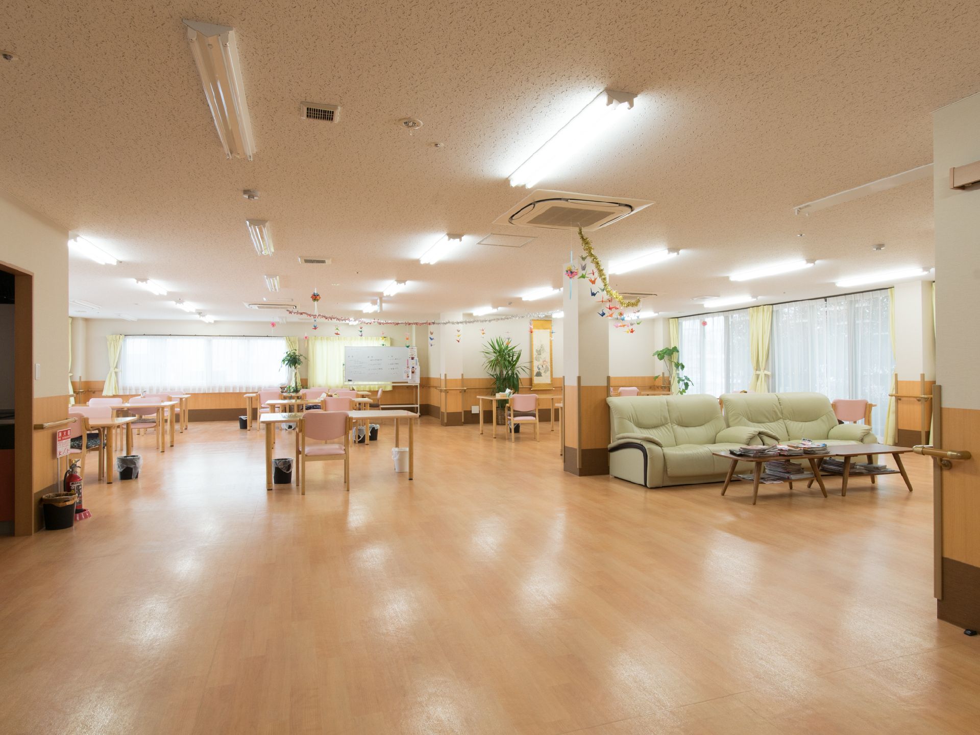 広々とした部屋はゆったりとテーブルと椅子が配置されている。ソファが置いてありくつろぐことができる。大きな窓があり、明るい空間になっている。