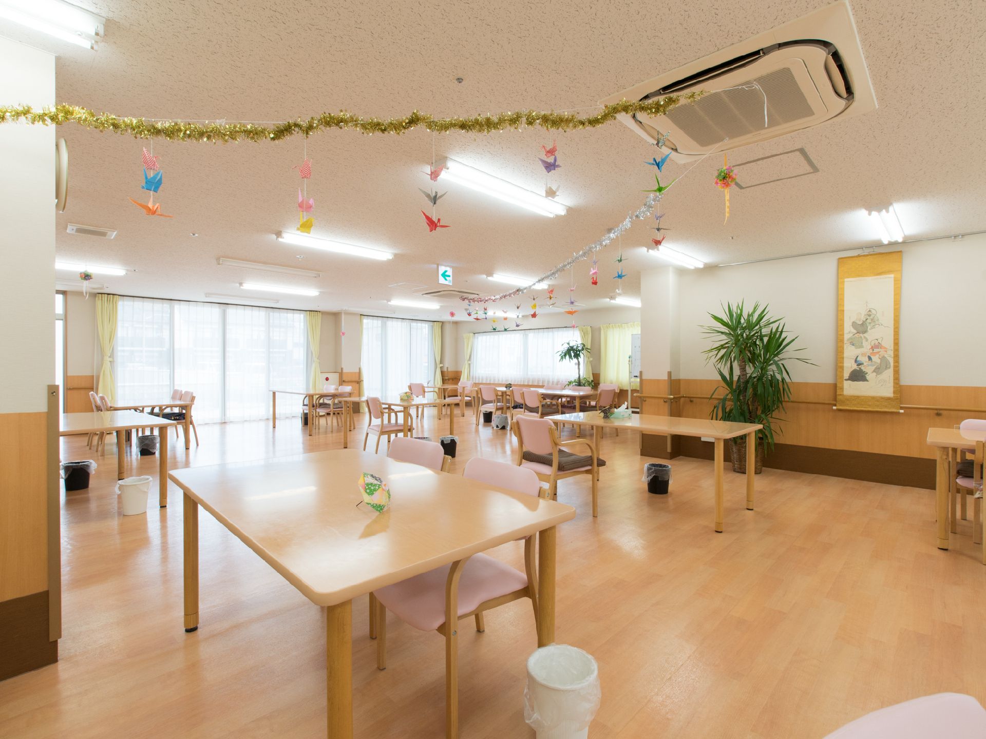 大きな窓があり、外からの光が入る明るい部屋で、天井から鶴などの飾りがつるされている温かみのある空間になっている。