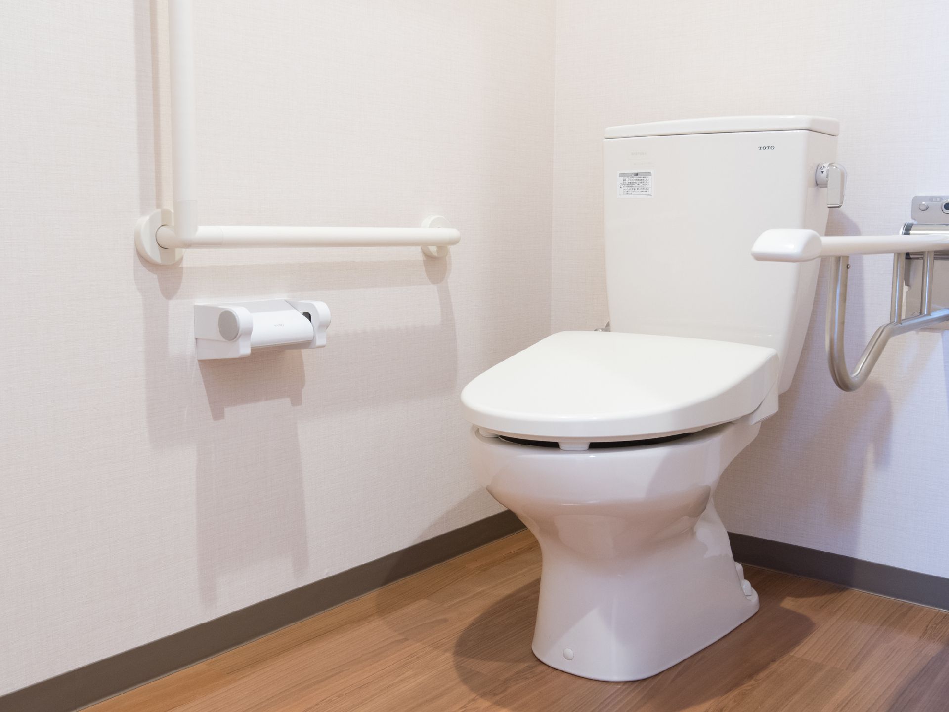 真っ白なトイレは清潔感があり、手すりが体の両側についているので安全に利用できる。床はフローリングで、落ち着いた雰囲気になっている。