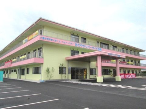 明るいグリーンにピンクの２色が特徴的な建物である。玄関の外は大きな屋根が設置されており、雨の日の出入りも安心して行える。