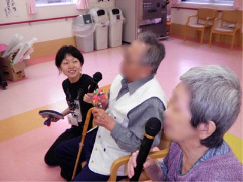 マイクを持っている高齢女性と、杖を持っている高齢男性にマイクを差し出している女性職員
