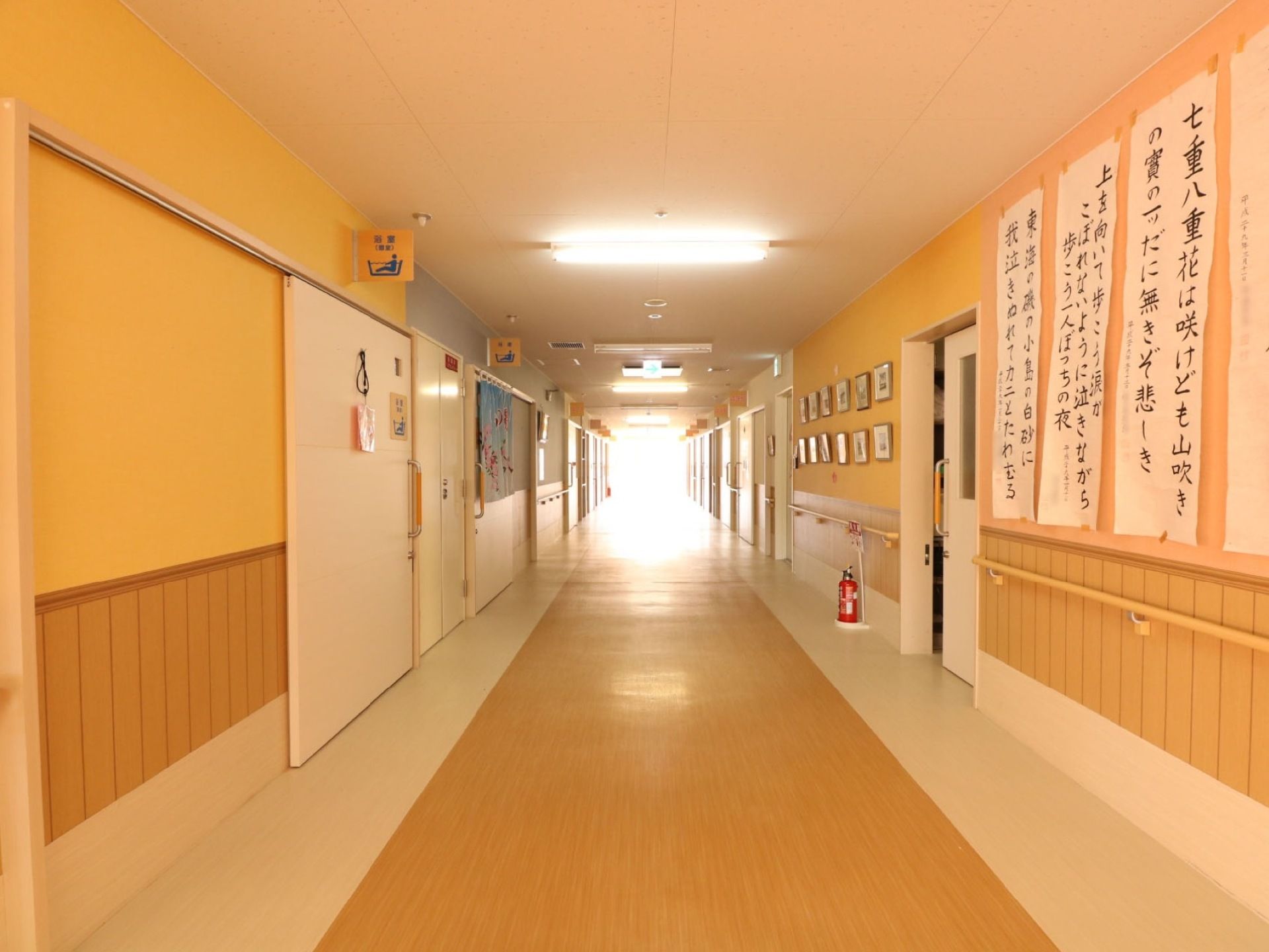長い通路の突き当りが光で輝いている。片側の壁に習字のような文字で書かれた紙が貼られ、床に消火器が置いてある。