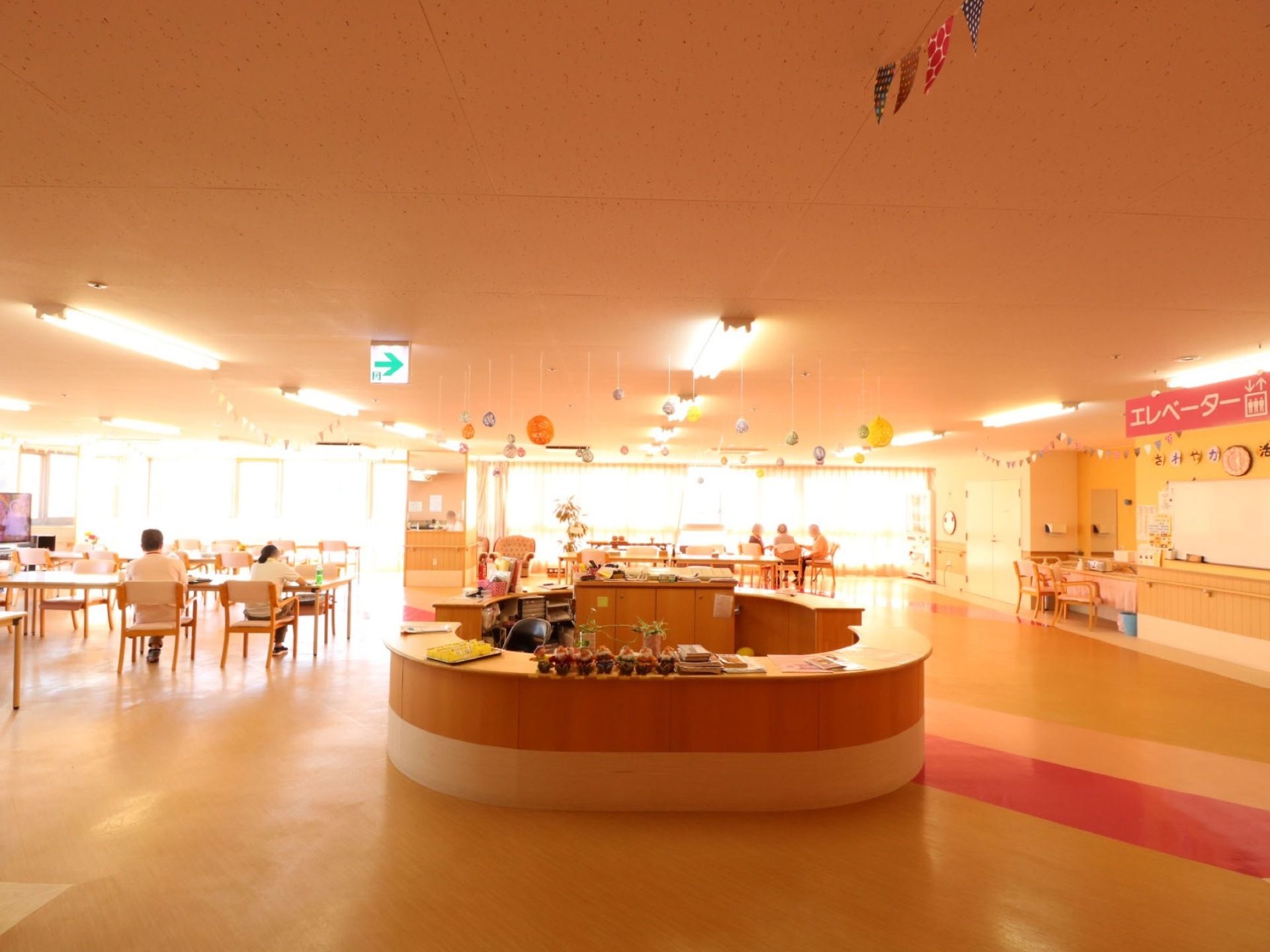 円形状に配置されたカウンターがある。たくさんのテーブルや椅子があり、数人が点在して椅子に腰を掛けている。