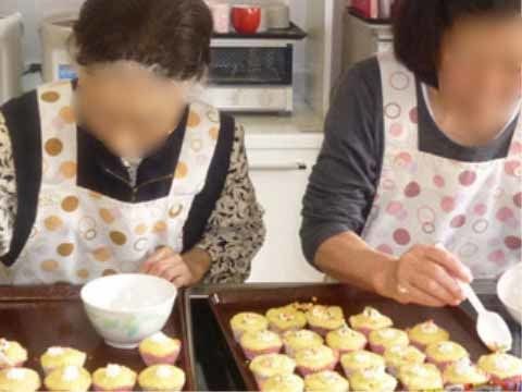 ダークブラウンのお盆に並んだお菓子に飾り付けをしているエプロンをかけた二人の女性