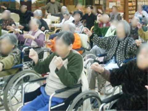 椅子や車椅子に座って両手を握って動かす運動に取り組んでいる高齢者