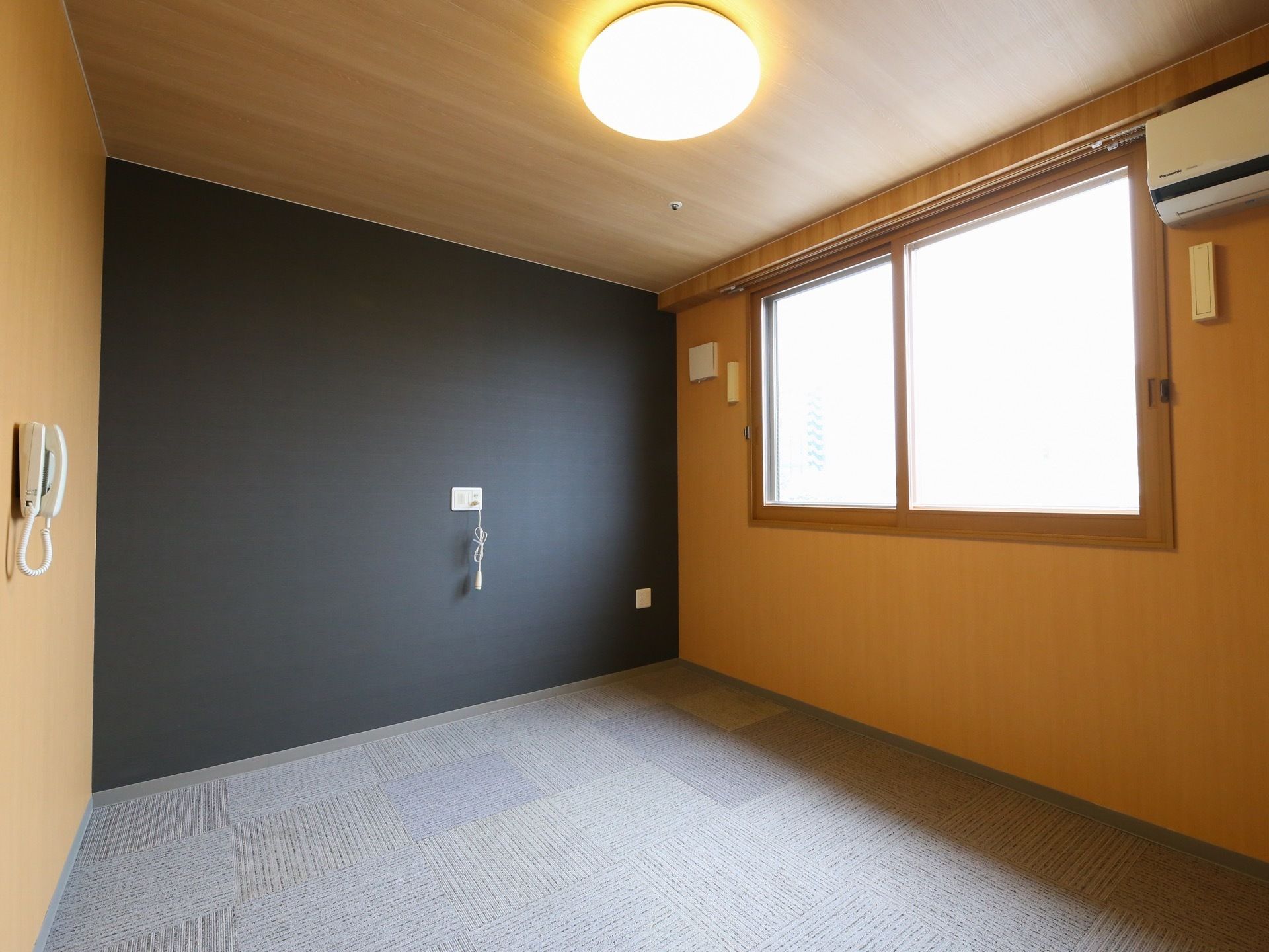 黒と木目調で統一されたシックな雰囲気のある居室である。LEDライトやエアコン、電話、ナースコールが完備されている。