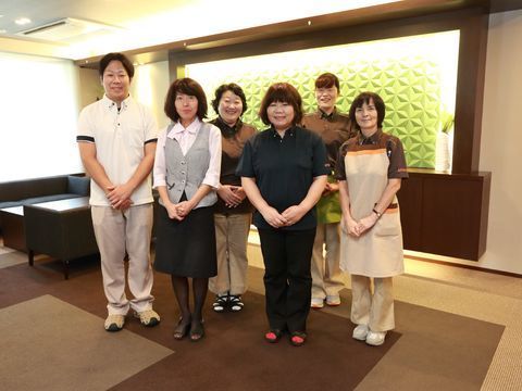 ブラウン系の内装の部屋に並ぶ5人の女性スタッフと1人の男性スタッフ