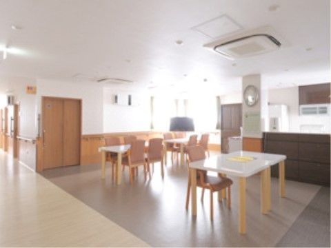 左奥に廊下が伸び、正面に窓が取られた、白いテーブルが並ぶ食堂