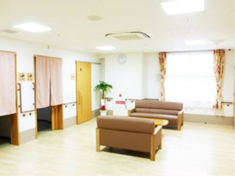 正面に窓がある室内は広くて明るい。窓に向かって左手にはのれんが掛かった入口が２カ所、引き戸式の扉が１カ所ある。中央にソファがある。