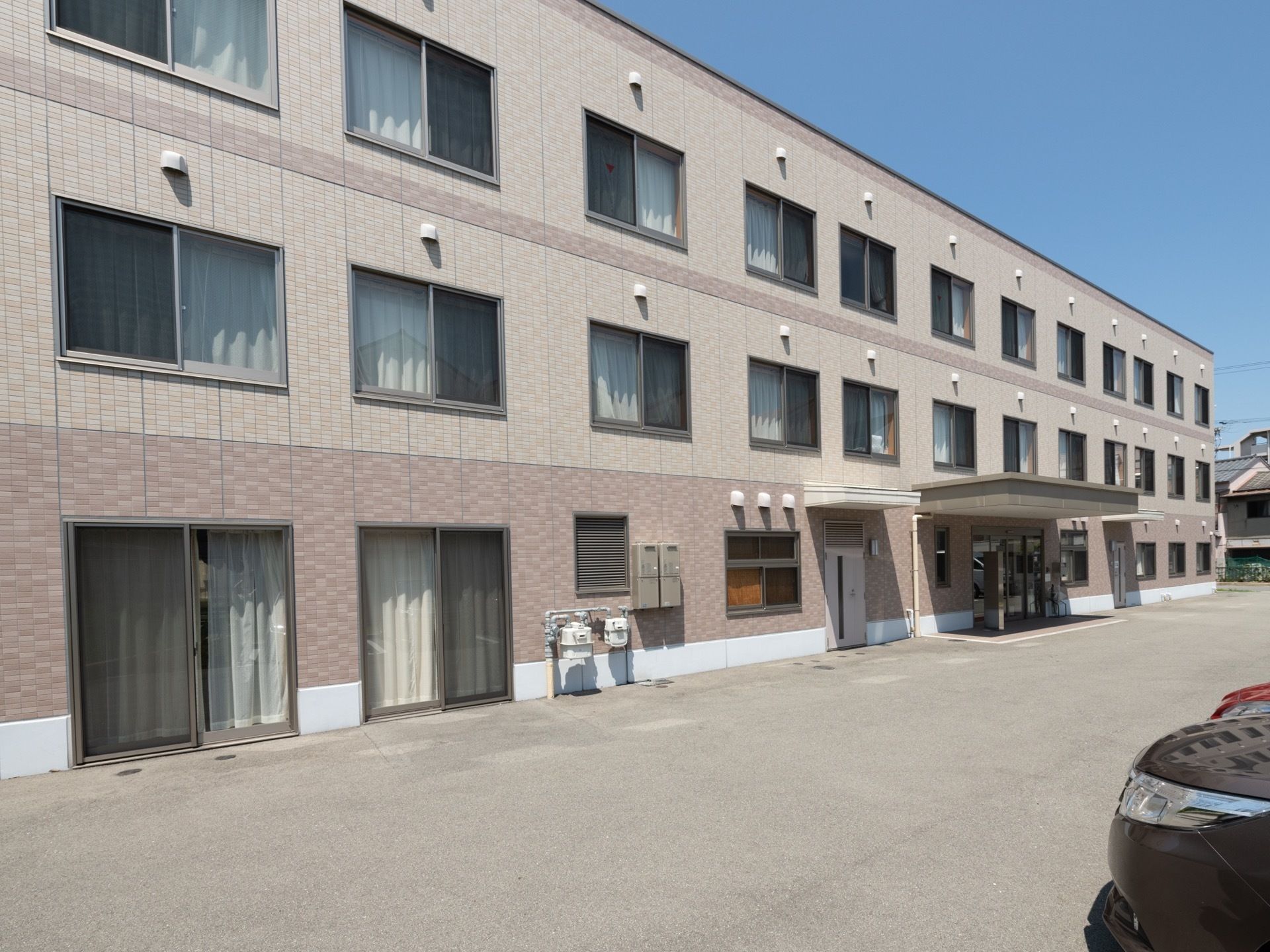 シンプルなすっきりとした外観の３階建ての建物である。すぐそばには駐車スペースが用意されており、移動が楽になっている。