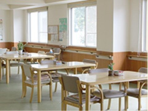 白とブラウンの壁、薄緑の床にテーブルセットが並んでいる食堂