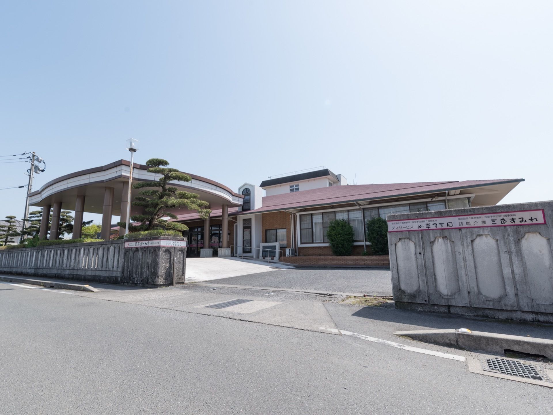 平屋建ての赤い屋根の建物である。施設と道路はコンクリートの壁で仕切られている。入り口には照明が設置され、松の木が植えられている。