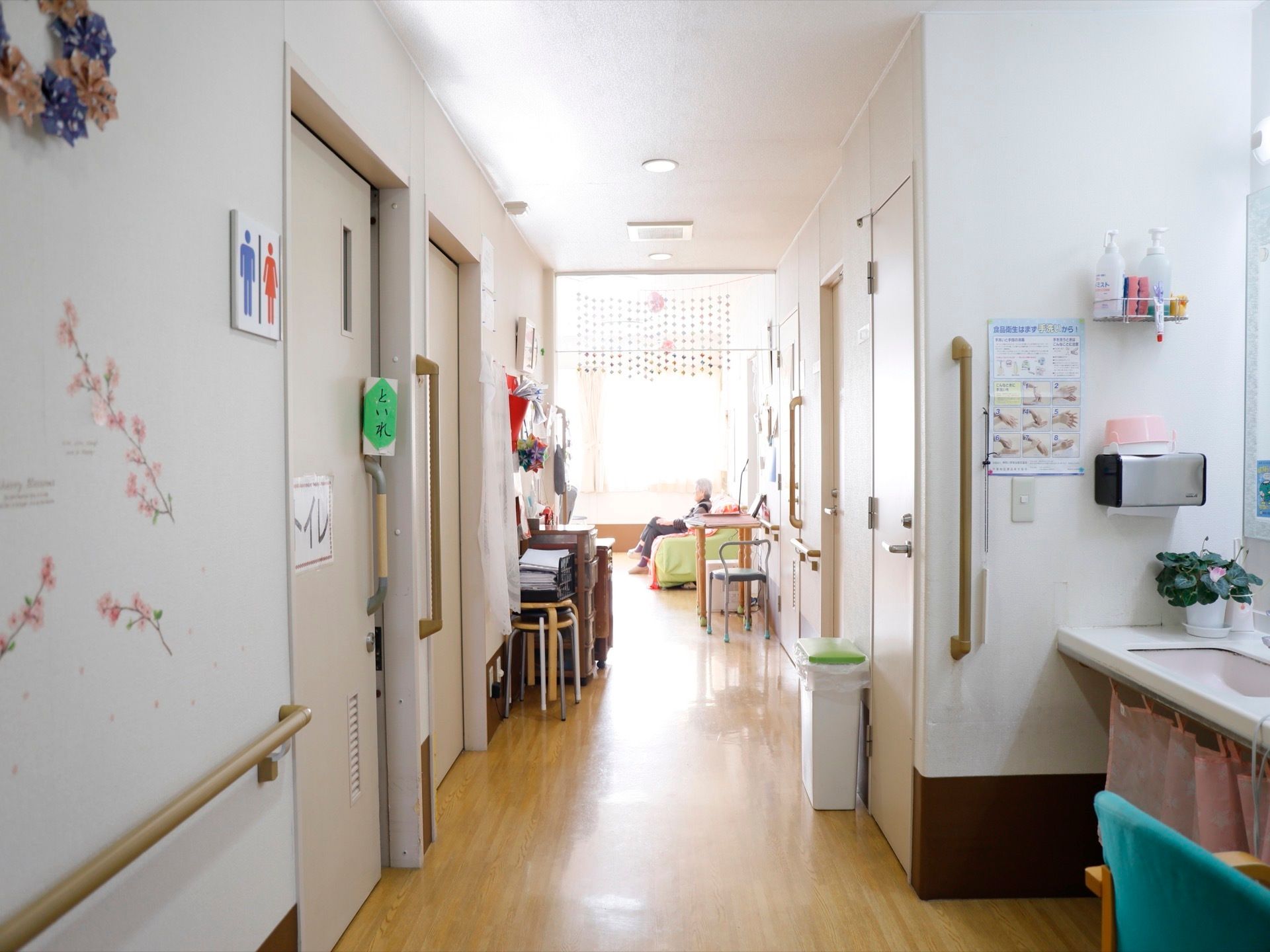 トイレ前の通路には洗面スペースを配置している。壁には複数の手すりを設置し、さまざまな花の飾り付けを施している。