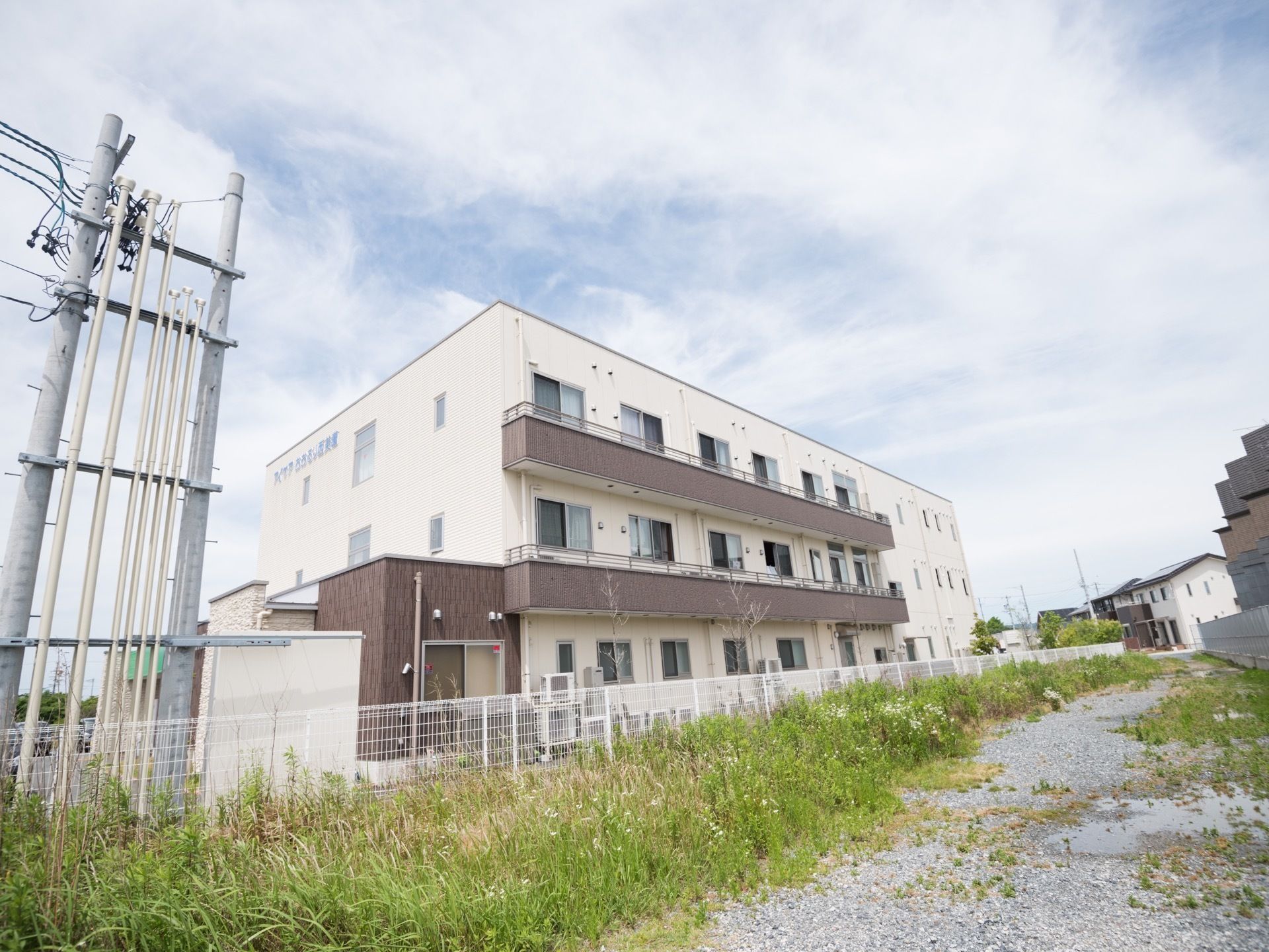 住宅街の中にある、白と茶色を基調とした落ち着いた色合いの３階建ての大きな建物である。周辺に高い建物はない。