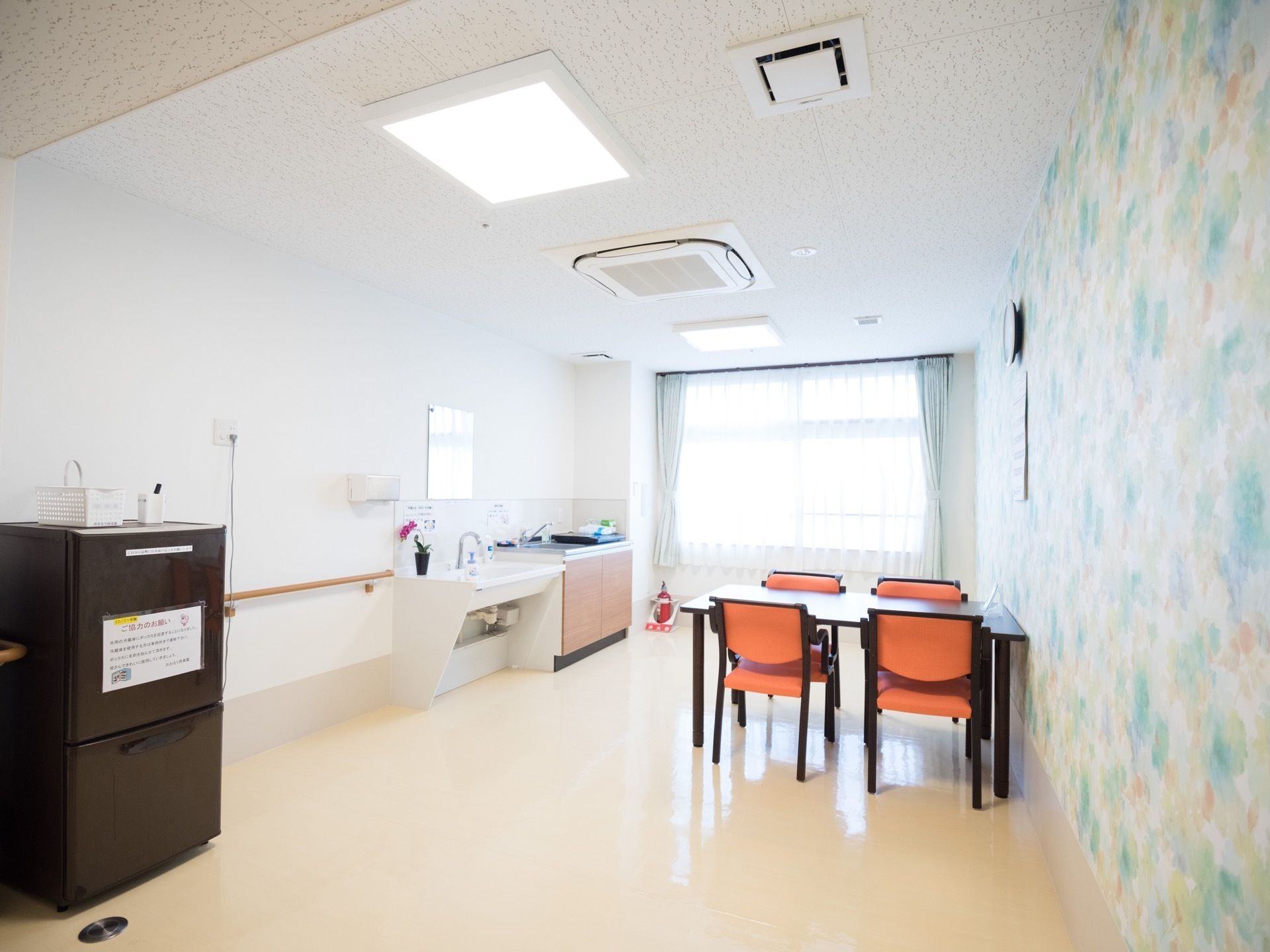 明るく開放的な共有スペースに、4人掛けのテーブルと椅子が置かれている。冷蔵庫の上には、黒いペンが用意されている。