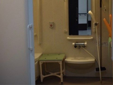 シャワー台の上には大きな鏡が取り付けられている。その両側には手すりが設置されている。壁にはスタッフの呼び出しボタンがある。