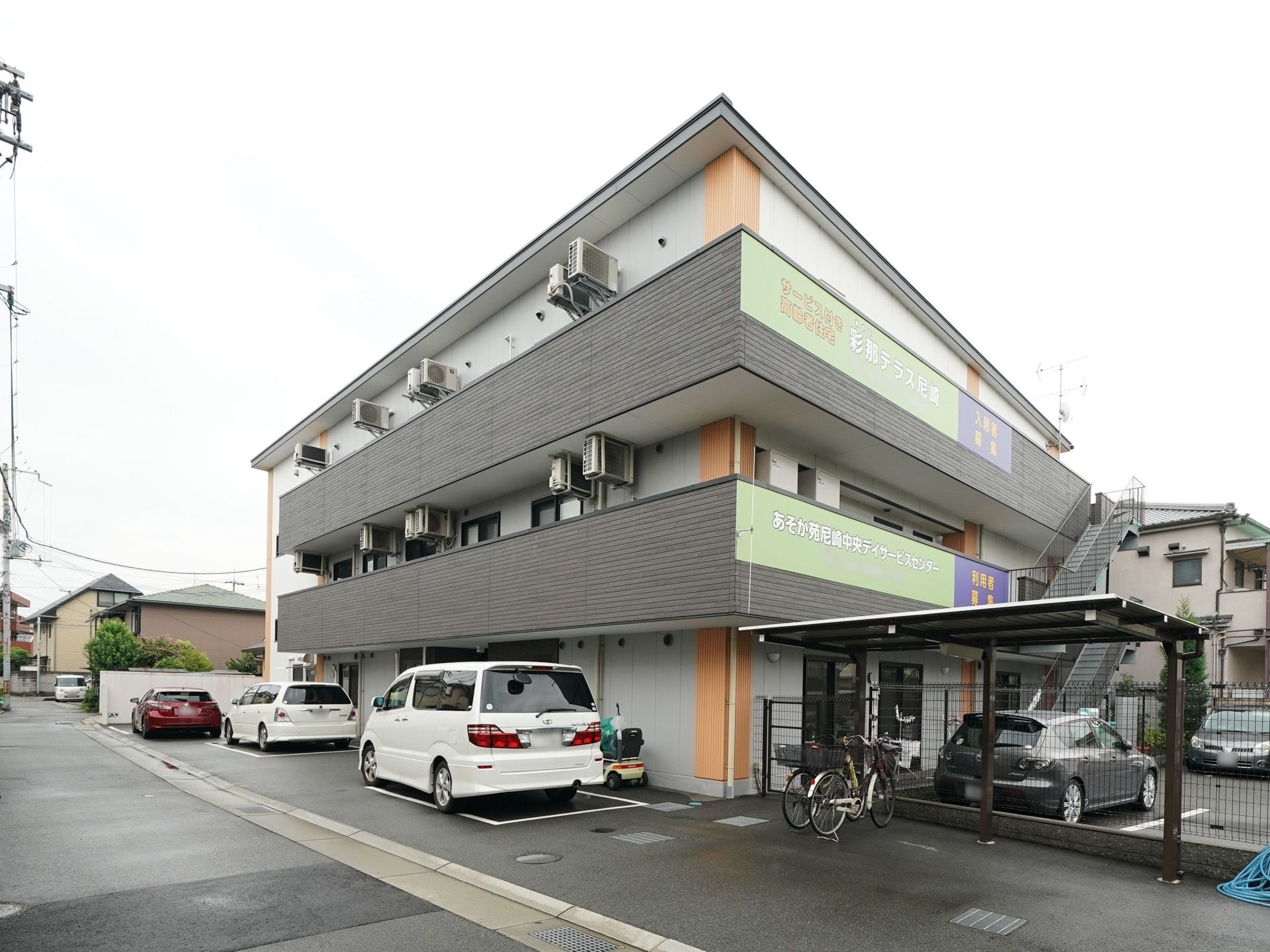 グレーを基調とした建物は、窓枠の黒がアクセントになっている。３階建てになっており、災害時の避難に利用できる外階段が設けられている。