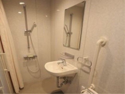 鏡付き洗面台と、シャワー、トイレが設置されている。壁面には手すりが付いている。ドアは引き戸になっている。