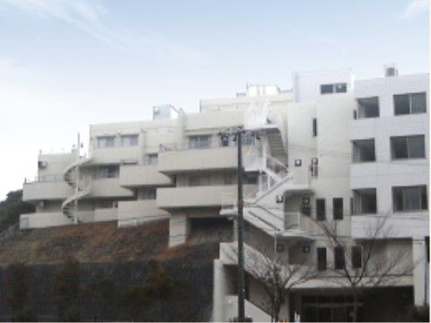 左奥にらせん階段、右手前に外階段がある白い外観の建物