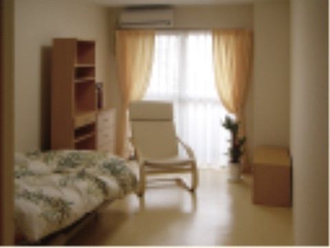 奥に窓があり、左壁面にチェストや棚、ベッドが並んでいる居室