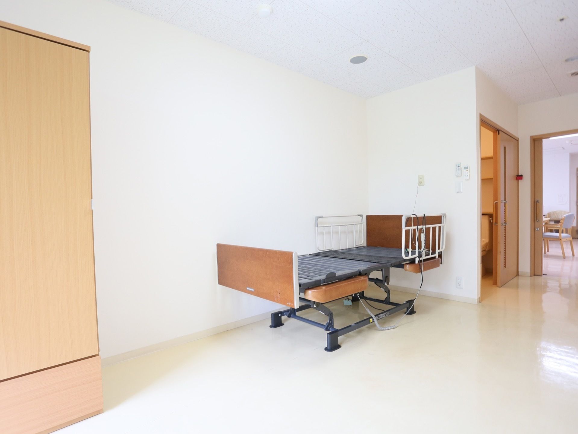 白いフローリングの部屋には、ベッドが設置されている。トイレに通じるドアは開け閉めしやすいスライド式である。