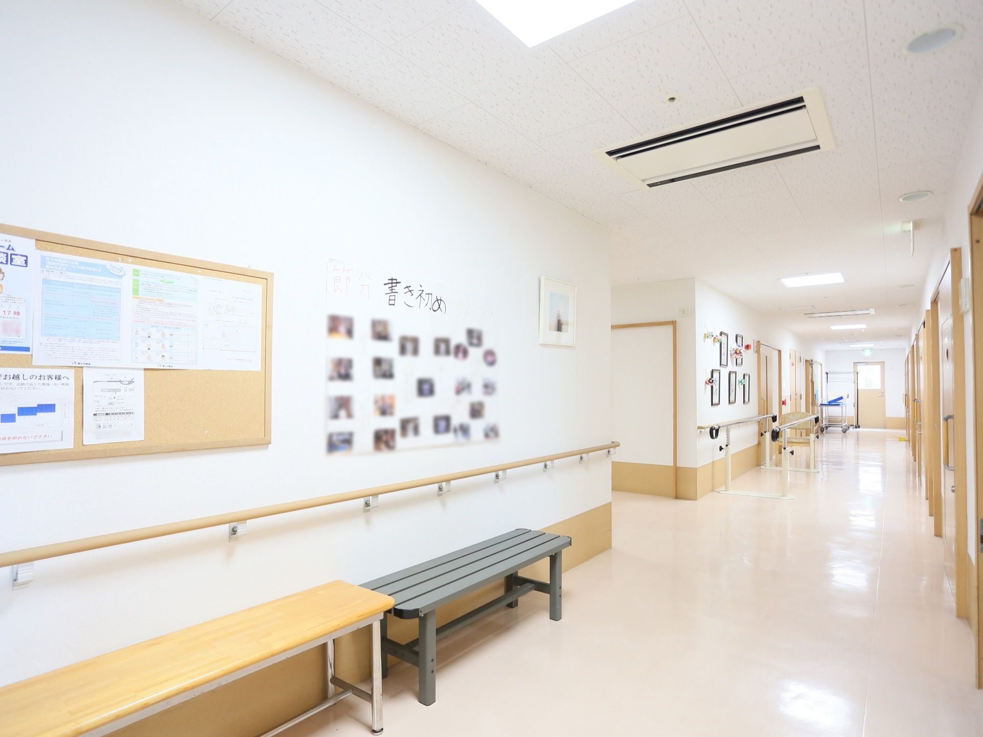 廊下がまっすぐに続いている。壁に沿って手すりがある。壁の近くには横に長いベンチが２種類並べて置かれている。