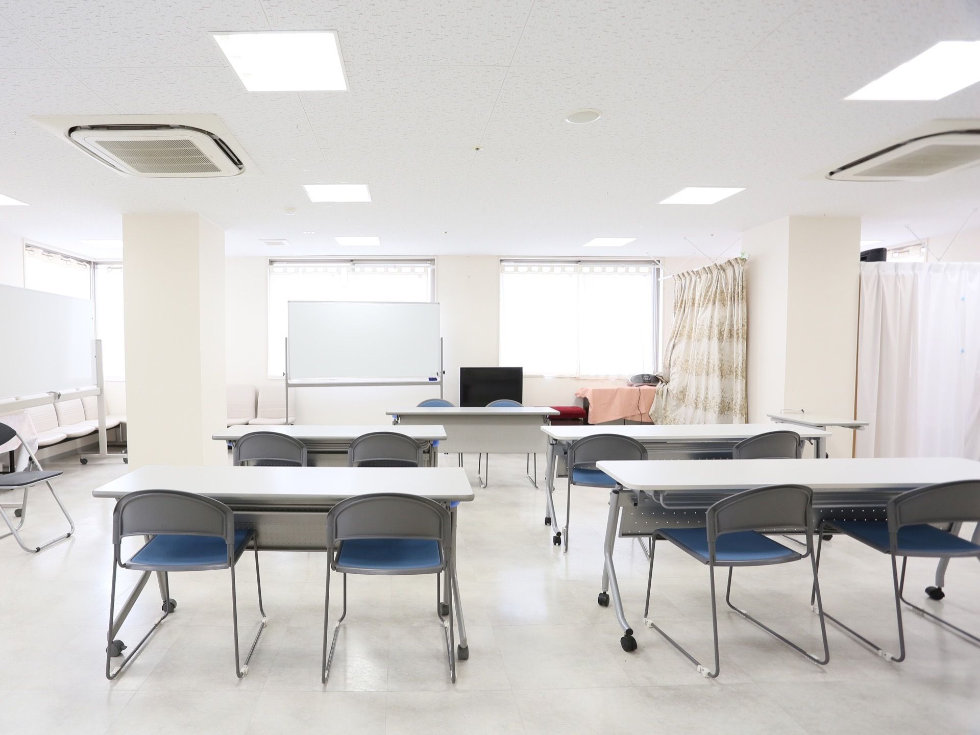 教室のようにテーブルと椅子が配置され、話をする側と聞く側が向かい合う形になっている。可動式のホワイトボードが設置されている。