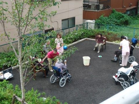 屋外スペースで椅子や車椅子に座ってレクリエーションに参加する高齢者