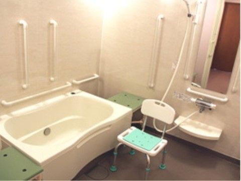 まごころの家 土浦上高津の浴室。グレーの床に白の壁とシックな空間でいたるところに手すりが完備されている。