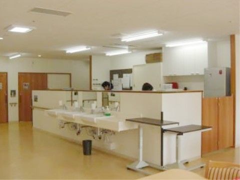 肩の高さほどの白い壁と、木製の扉が付いたスペースにケアステーションがある。入居者様が共有している部分に面している。
