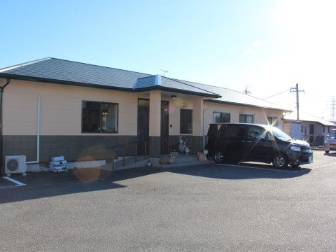 淡いオレンジとブラウンに切り替えられた壁面で緑の寄棟屋根の平屋の建物