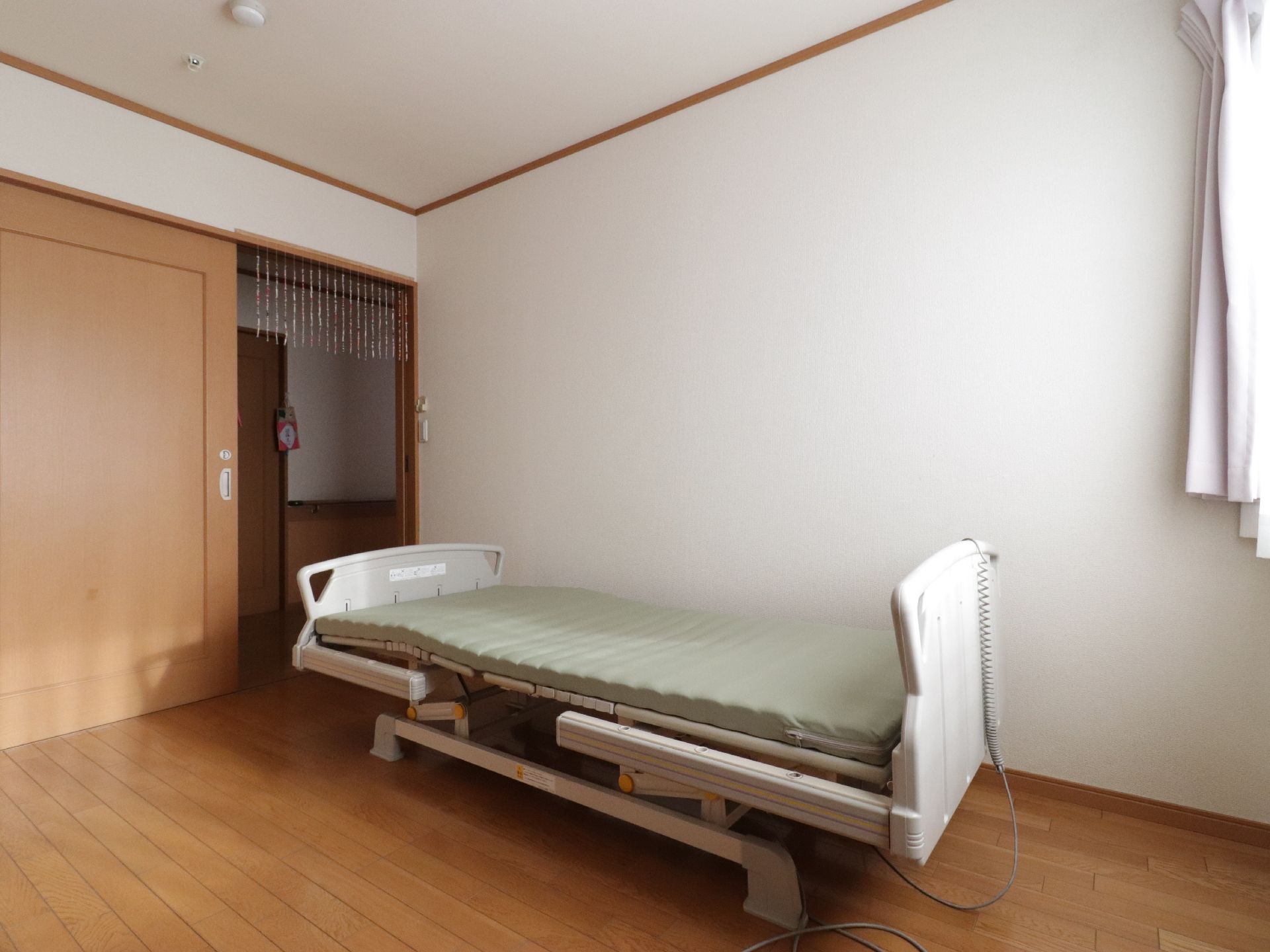居室には大きな扉が取り付けられている。中にはベッドが設置されている。窓には2種類のカーテンが掛かっている。