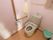 トイレには洋式便器が設置されている。左側にはタオルが掛かったタオルハンガー、手すり、トイレットペーパーフォルダーがある。