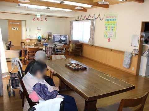 左奥にドア、右奥に窓があり、窓の下にテレビが置かれた共用スペース