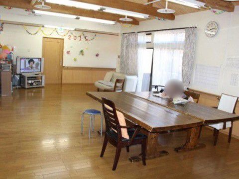 右奥に窓があり、その前にソファが置かれた板張りの床の共用スペース