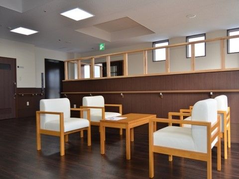 ダークブラウンを基調にした室内に、4人掛けの応接セットが置かれている。ドア付近や仕切り壁には、手すりが設置されている。