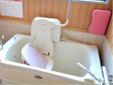 座ったまま入浴できる補助装置と給湯用の蛇口の付いた白い浴槽