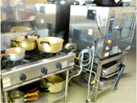 鍋が3つ乗った銀色のコンロの右に銀色の箱型の機械のある調理室