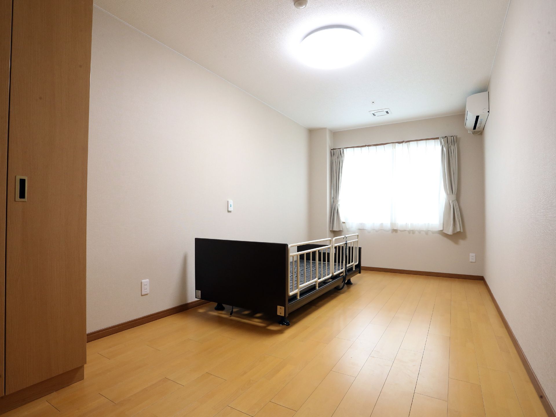 利用者の個室は、明るい窓があり収納も十分なクローゼットが設置され、ベッドには転落防止の柵がセットされている。
