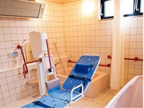 寝たままの姿勢で入浴できる青い補助装置があり、その手前に浴槽がある浴室