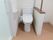 白色が基調のトイレは、便器に座って右側にトイレットペーパーが設置されている。また、扉が設置されておらず、開放的である。