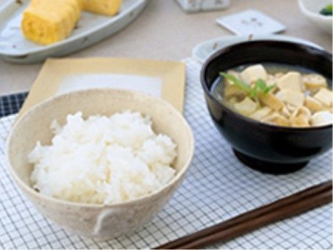 白いランチョンマットの上に置かれたご飯、みそ汁、お箸