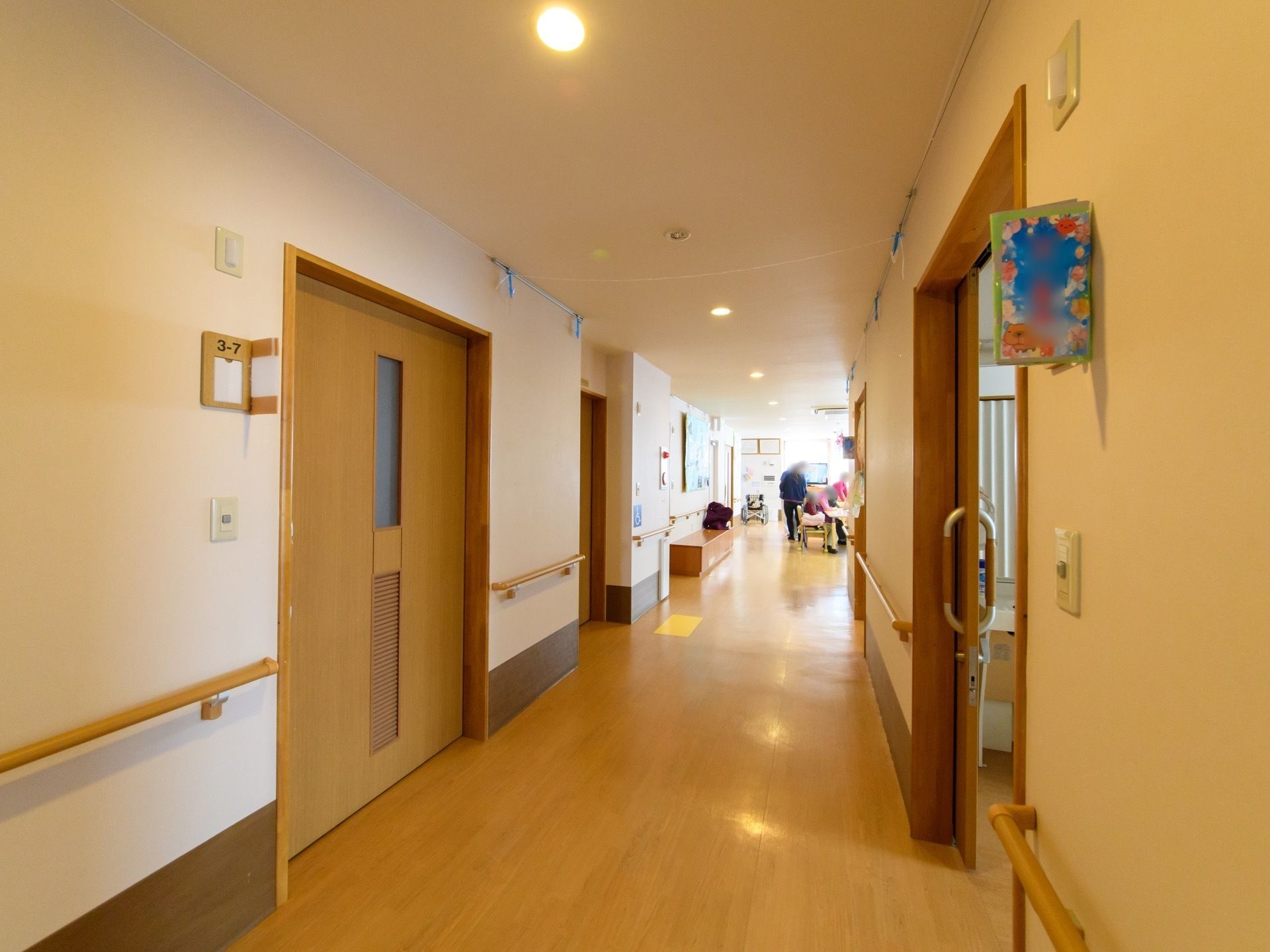 幅の広い廊下で、両サイドには居室がある。部屋のドアはスライド式で、壁の全てに手すりが設置されている。